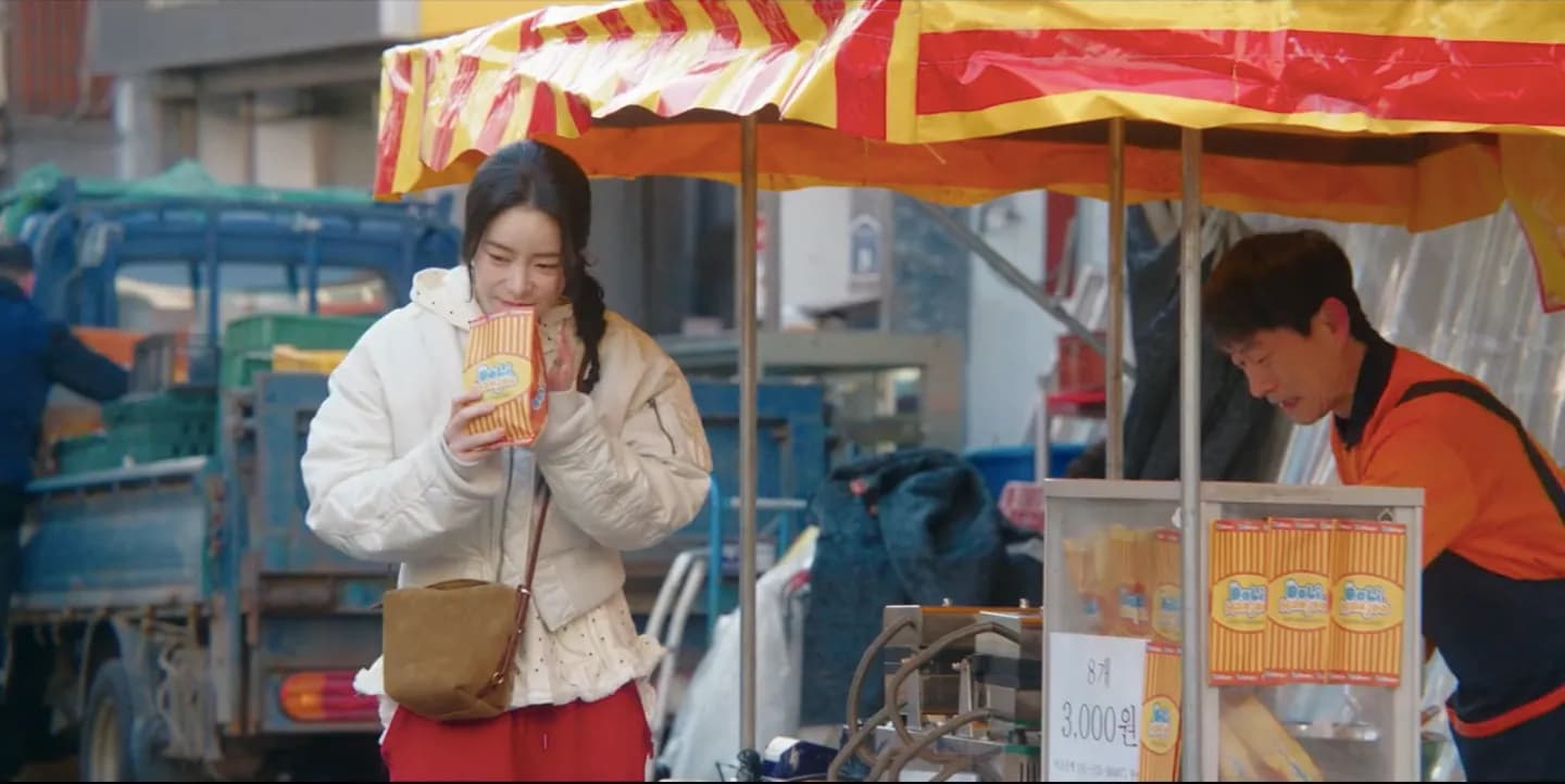 Seo-ri eating street food at a stall in the traditional market
