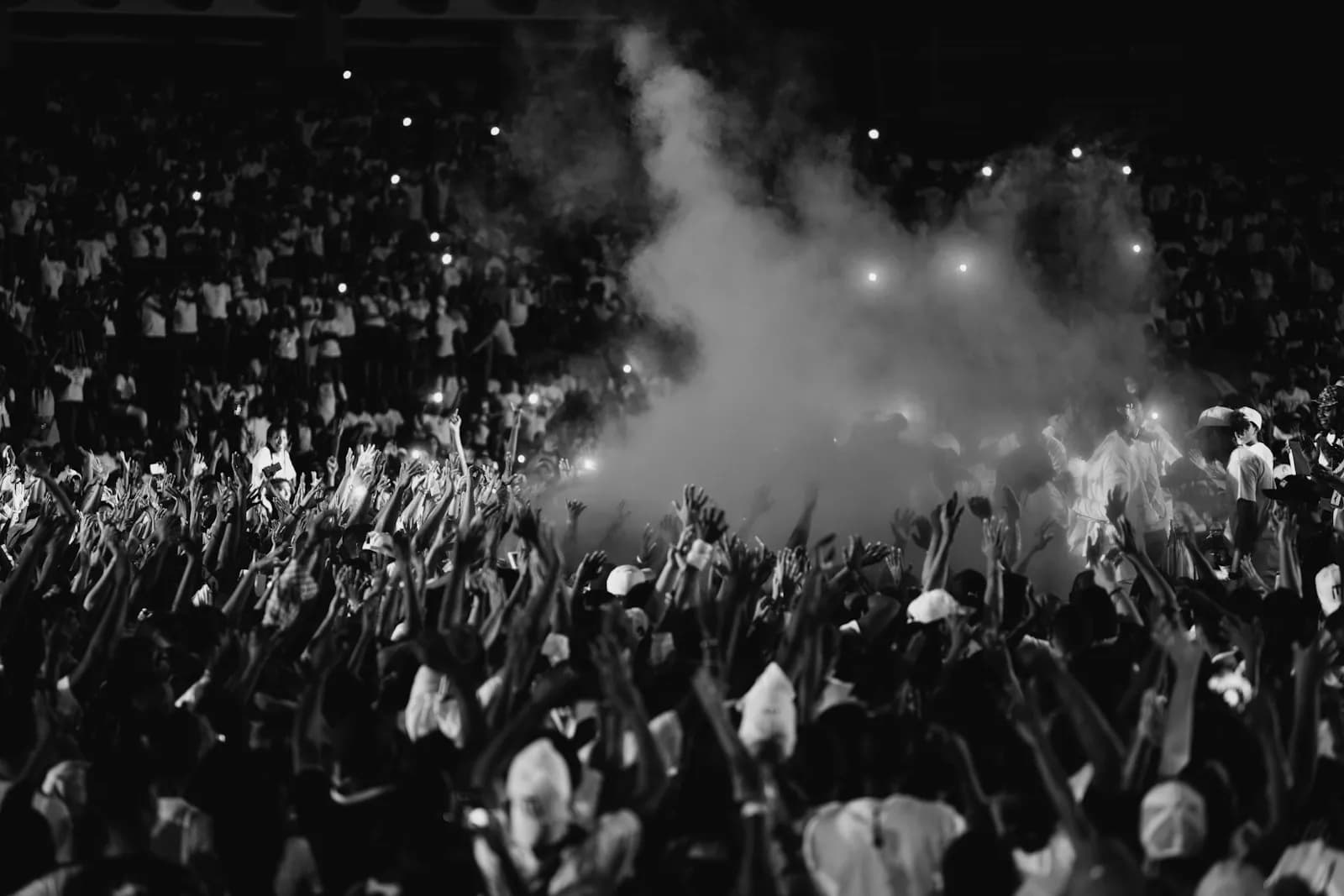 Concert audience cheering with lightsticks and phones held up