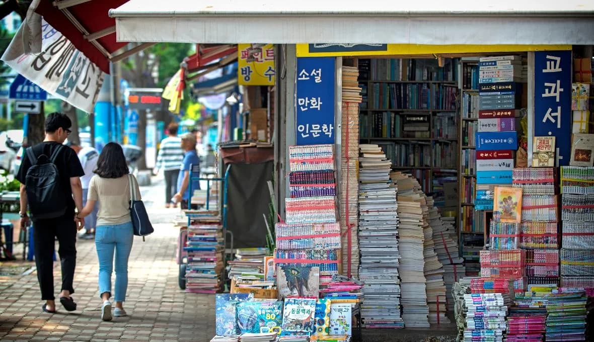 Walkers browsing book stacks lining the open-air Bosu-dong Book Street