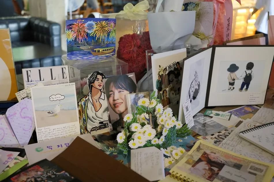 Table covered in ARMY letters, photos, and flowers dedicated to BTS Jimin inside ZM-illennial cafe