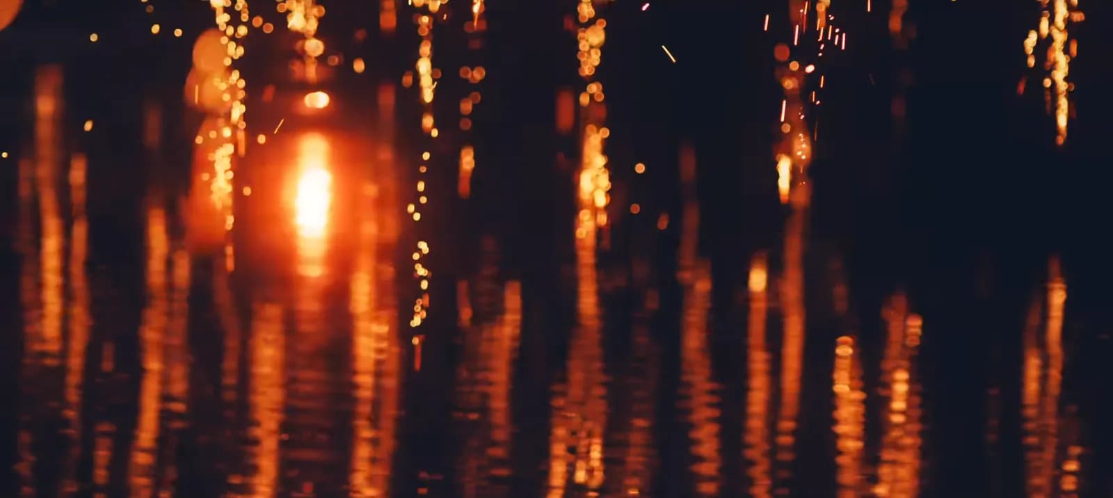 Nakhwanori fire-flower sparks cascading from ropes above Mujinjeong pond in Haman, doubled in the water reflection
