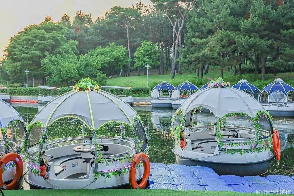 Transparent dome boats docked at Songdo Central Park with pine trees in the background
