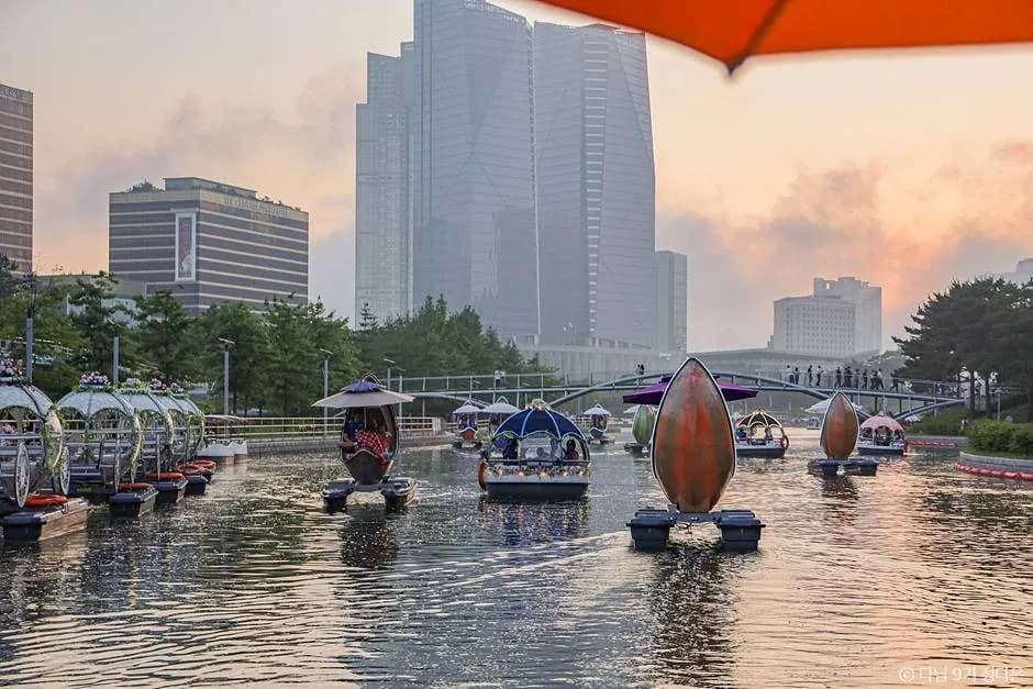 Boats on the Songdo Central Park waterway with skyscrapers and sunset sky