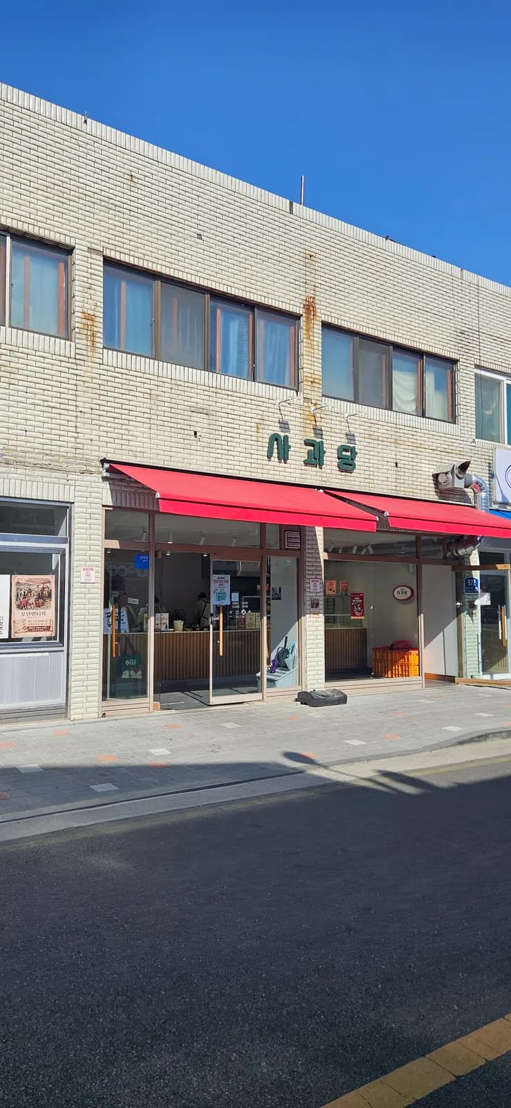 Side view of a Yesan Traditional Market shop with red awnings and hanging signage