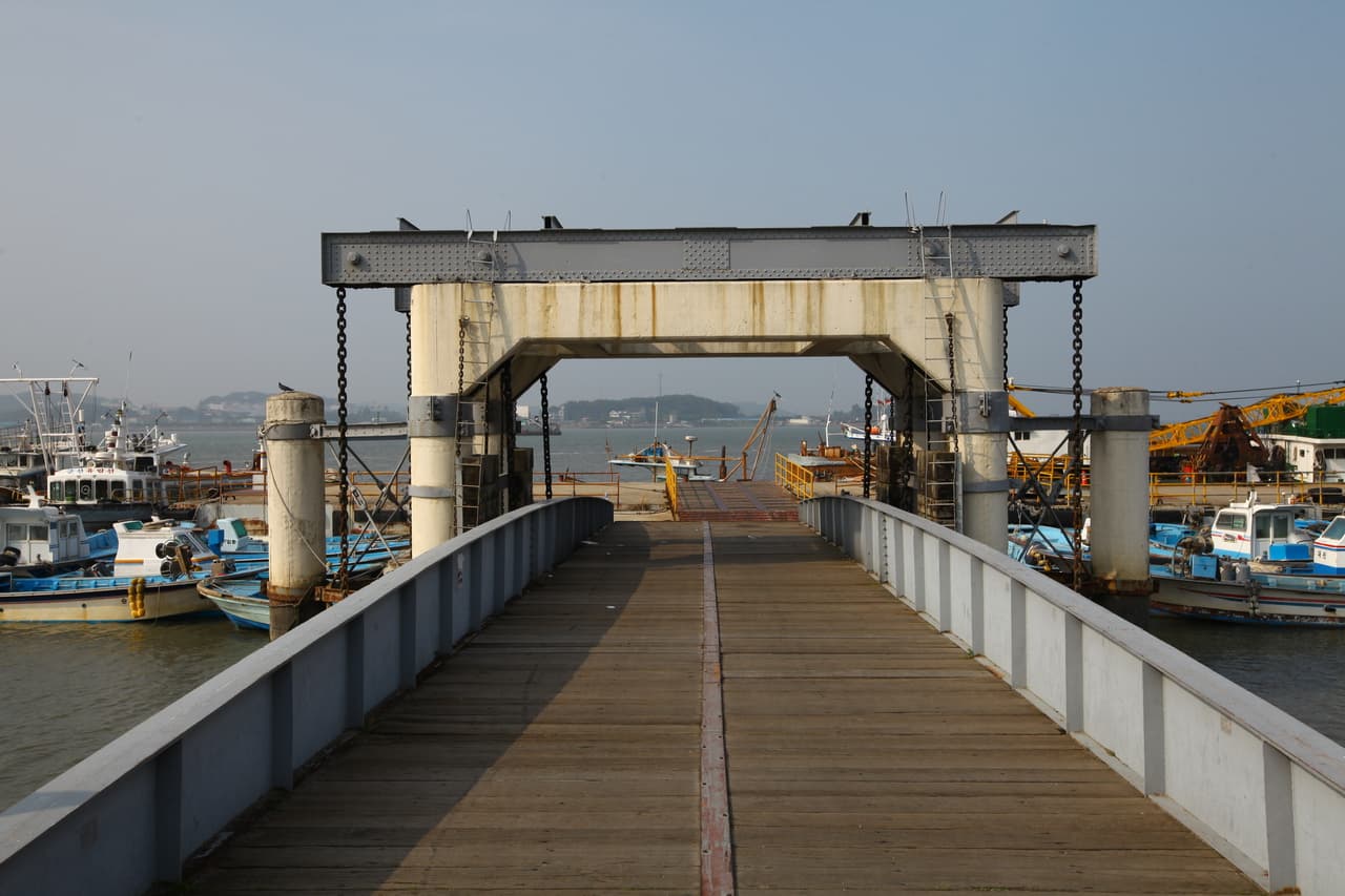 Walking onto the floating pier gantry with fishing boats moored on both sides at Gunsan inner port