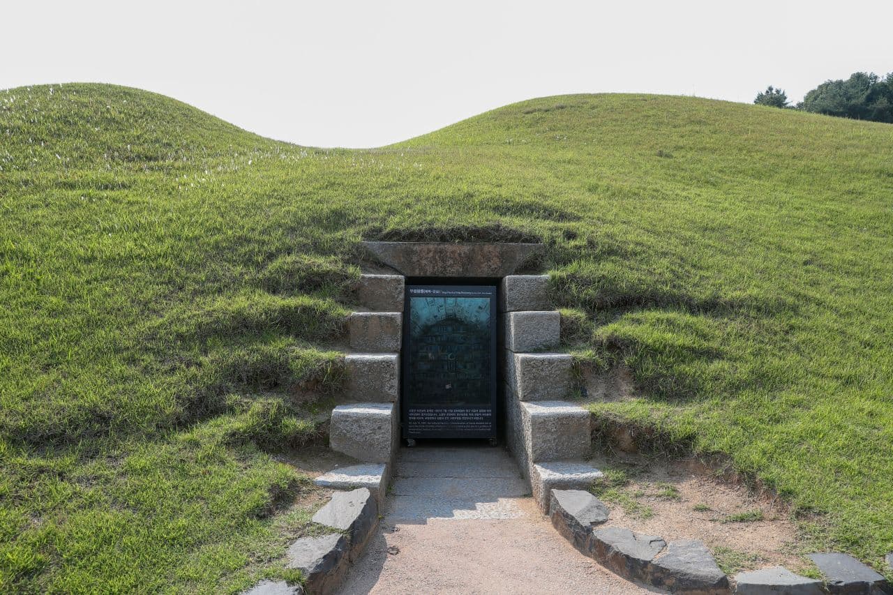 Stone entrance set into a grass-covered Baekje royal burial mound at Songsan-ri