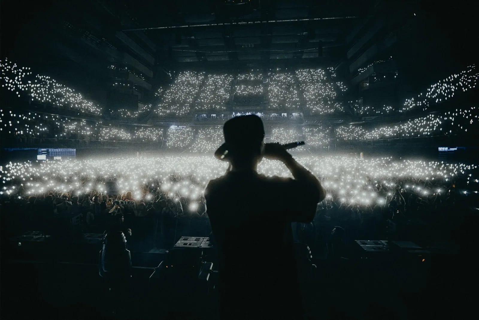 A glowing K-pop lightstick held above a crowd at a Korean concert venue