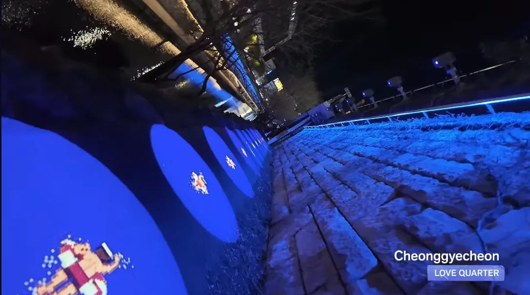Fans walking along Cheonggyecheon under the BTS ARIRANG Light Walk installations