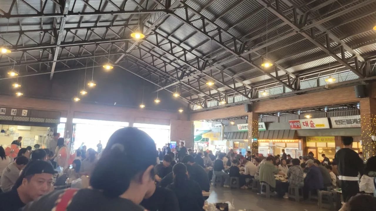 Packed communal dining hall at Yesan Traditional Market with shared tables and visitors