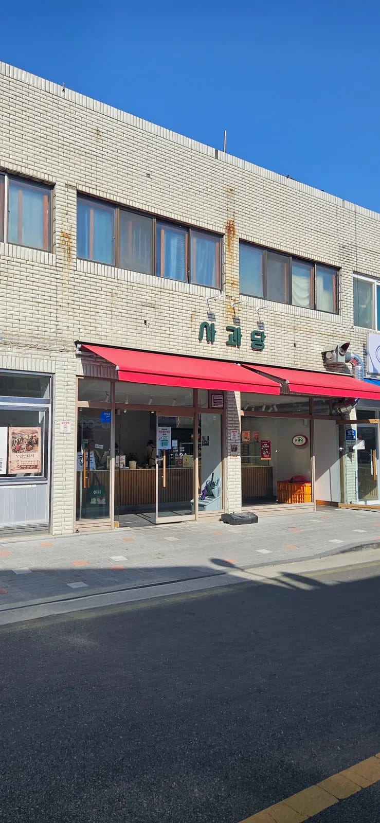 Side view of a Yesan Traditional Market shop with red awnings and hanging signage