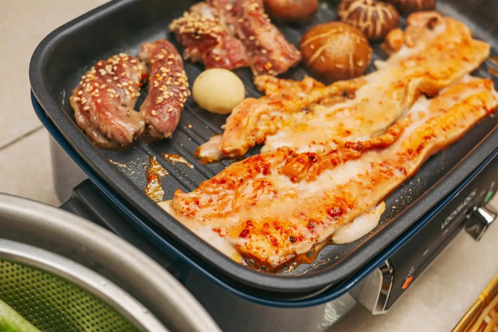Sizzling samgyeopsal pork belly on a Korean BBQ grill with banchan side dishes