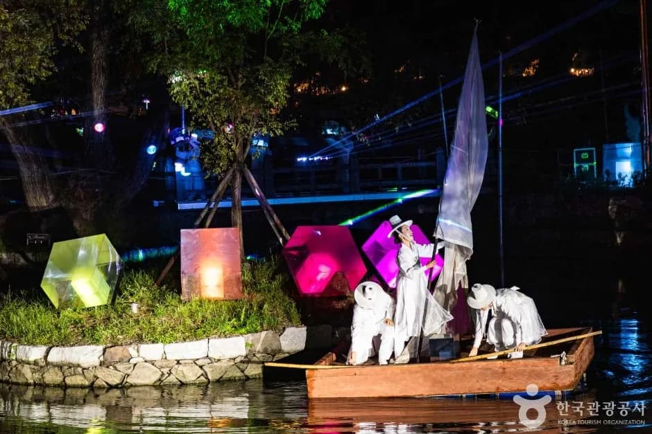 Performers in white traditional robes on a raft during the Nakhwanori ceremony